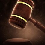 A wooden judge’s gavel held above a round sound block with a dark, softly lit background. - Ghassemi Law Group A wooden judge’s gavel held above a round sound block with a dark, softly lit background