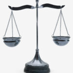 A metallic balance scale with two unevenly weighted pans hanging from each side, set against a white background