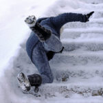 A person experiences a slip and falls on snowy outdoor steps, dressed in winter clothing and boots. - Ghassemi Law Group A person experiences a slip and falls on snowy outdoor steps, dressed in winter clothing and boots