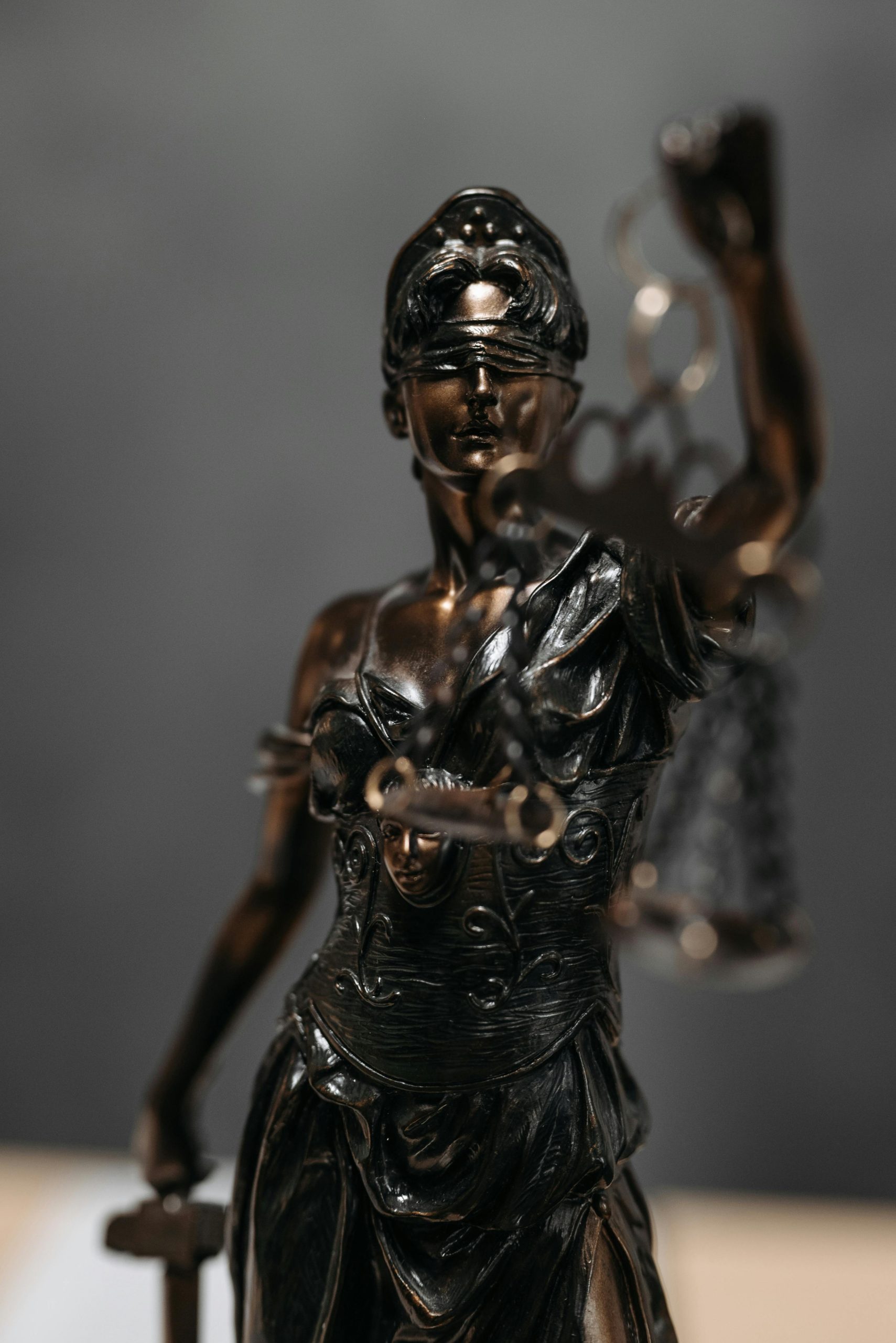 A bronze statue of Lady Justice holding scales and a sword, wearing a blindfold, stands against a blurred background—a symbol often invoked in wrongful death cases.