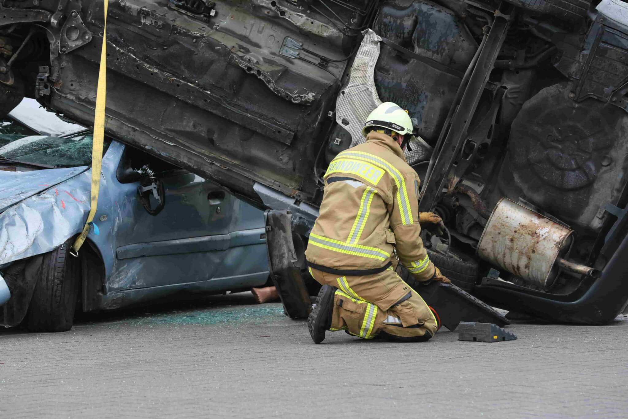 A firefighter in protective gear kneels beside an overturned vehicle stacked on a crushed car during a rescue operation—reminding us how vital expert help, like a Car Accident Lawyer in Irvine, can be when you need it most. - Ghassemi Law Group A firefighter in protective gear kneels beside an overturned vehicle stacked on a crushed car during a rescue operation—reminding us how vital expert help, like a Car Accident Lawyer in Irvine, can be when you need it most.
