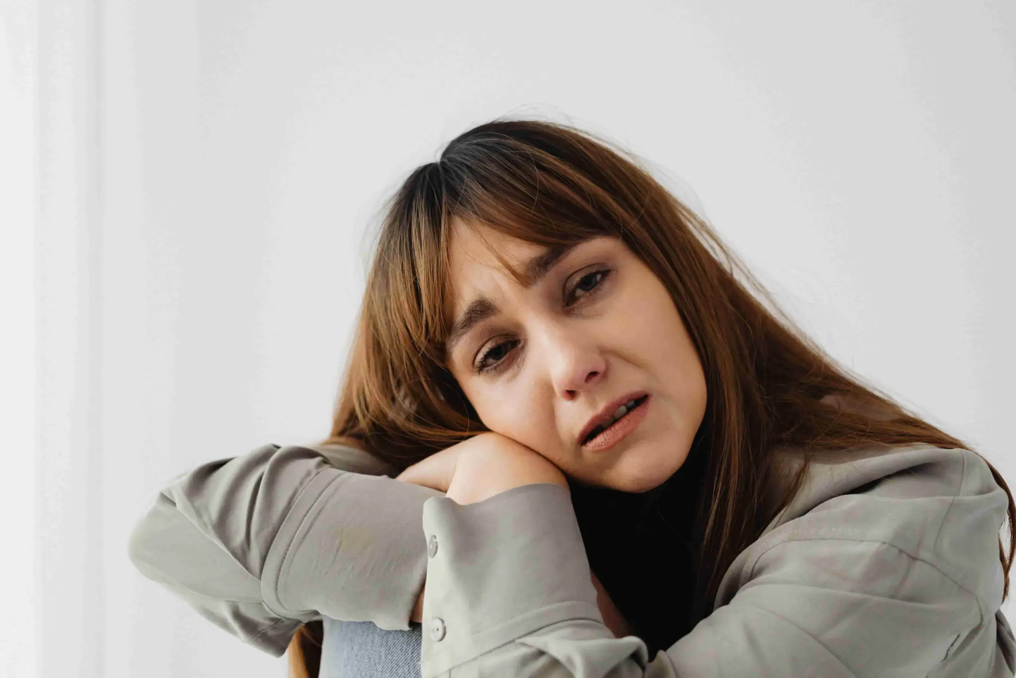 A woman with brown hair leans on her knees, looking distressed or upset, against a plain white background, depicting the emotional turmoil often experienced after an accident. Can I Sue for Emotional Distress After an Accident in Irvine?. - Ghassemi Law Group A woman with brown hair leans on her knees, looking distressed or upset, against a plain white background, depicting the emotional turmoil often experienced after an accident Can I Sue for Emotional Distress After an Accident in Irvine?
