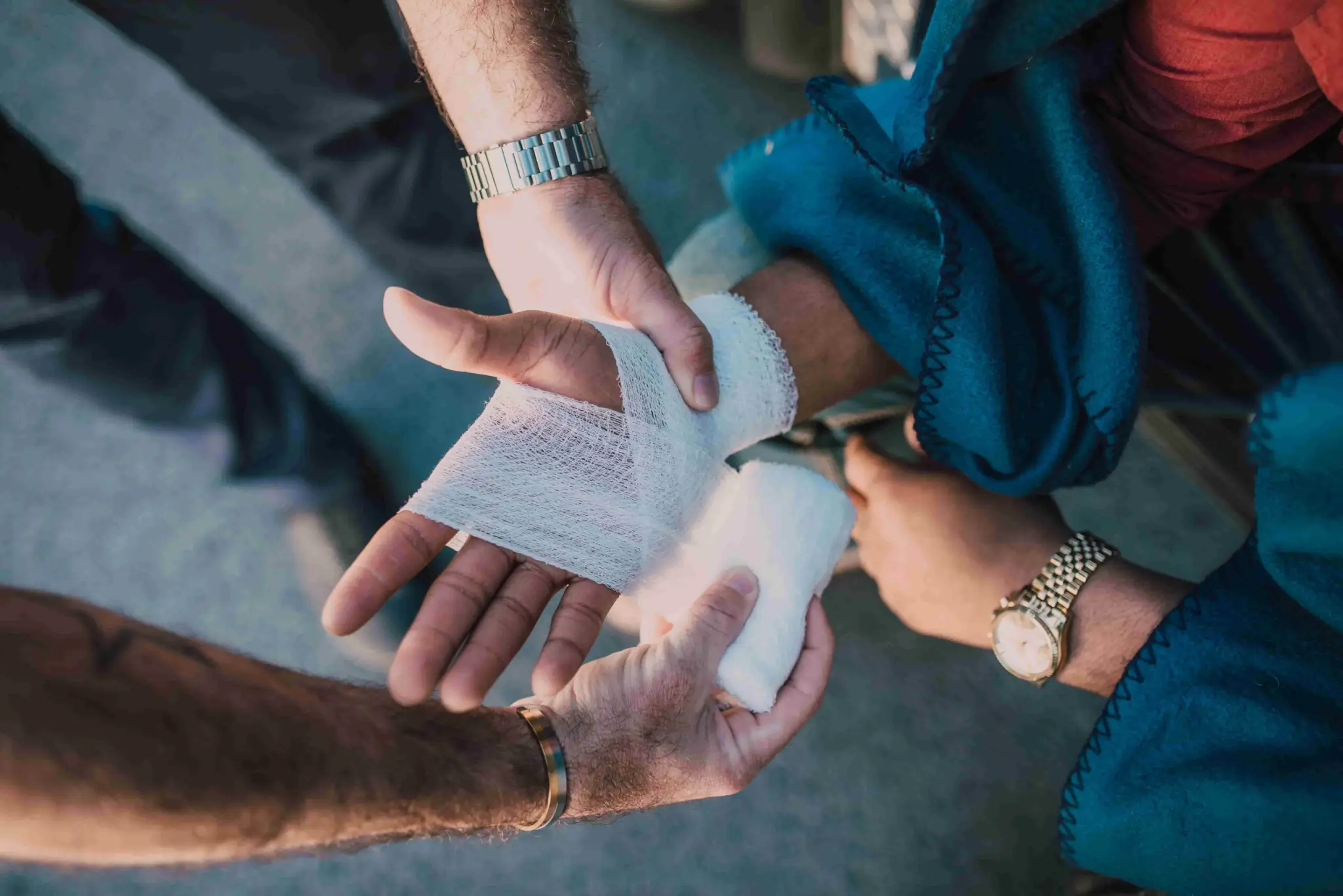 A person wraps gauze bandage around another person's injured hand while both are seated, raising the question: How Long Do I Have to File a Personal Injury Claim in Irvine?. - Ghassemi Law Group A person wraps gauze bandage around another person's injured hand while both are seated, raising the question: How Long Do I Have to File a Personal Injury Claim in Irvine?