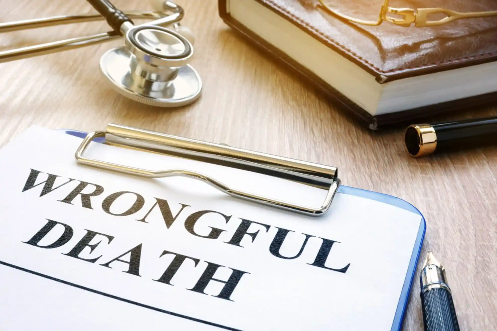 A clipboard with a paper labeled “WRONGFUL DEATH,” next to a stethoscope, book, glasses, and pen on a wooden desk highlights the critical documentation involved in wrongful death cases. - Ghassemi Law Group - Ghassemi Law Group A clipboard with a paper labeled “WRONGFUL DEATH,” next to a stethoscope, book, glasses, and pen on a wooden desk highlights the critical documentation involved in wrongful death cases