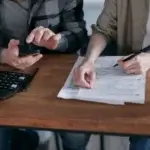 Two people reviewing financial paperwork with a calculator