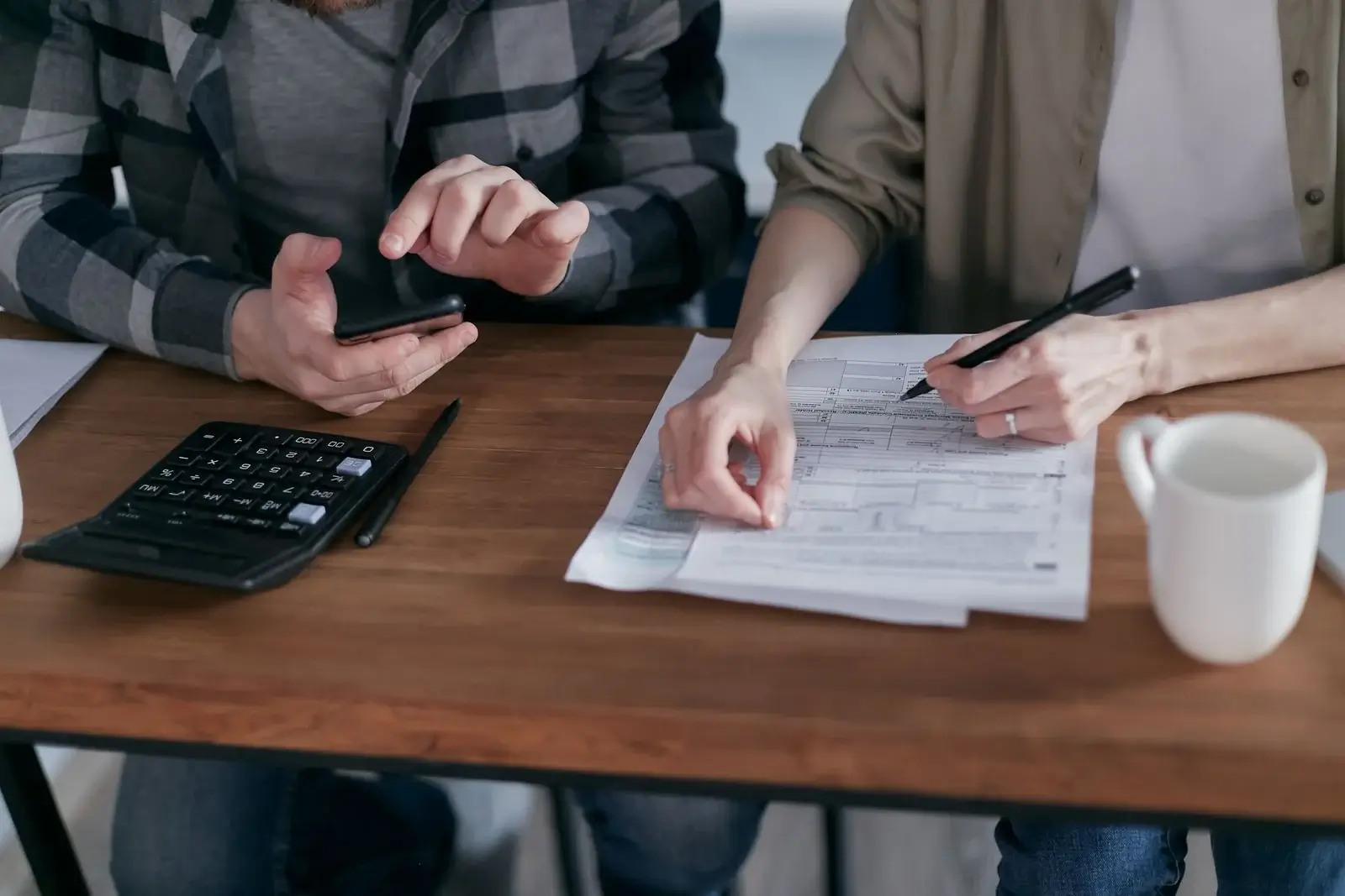 Two people reviewing financial paperwork with a calculator