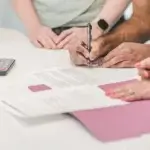People reviewing and signing documents together at a table