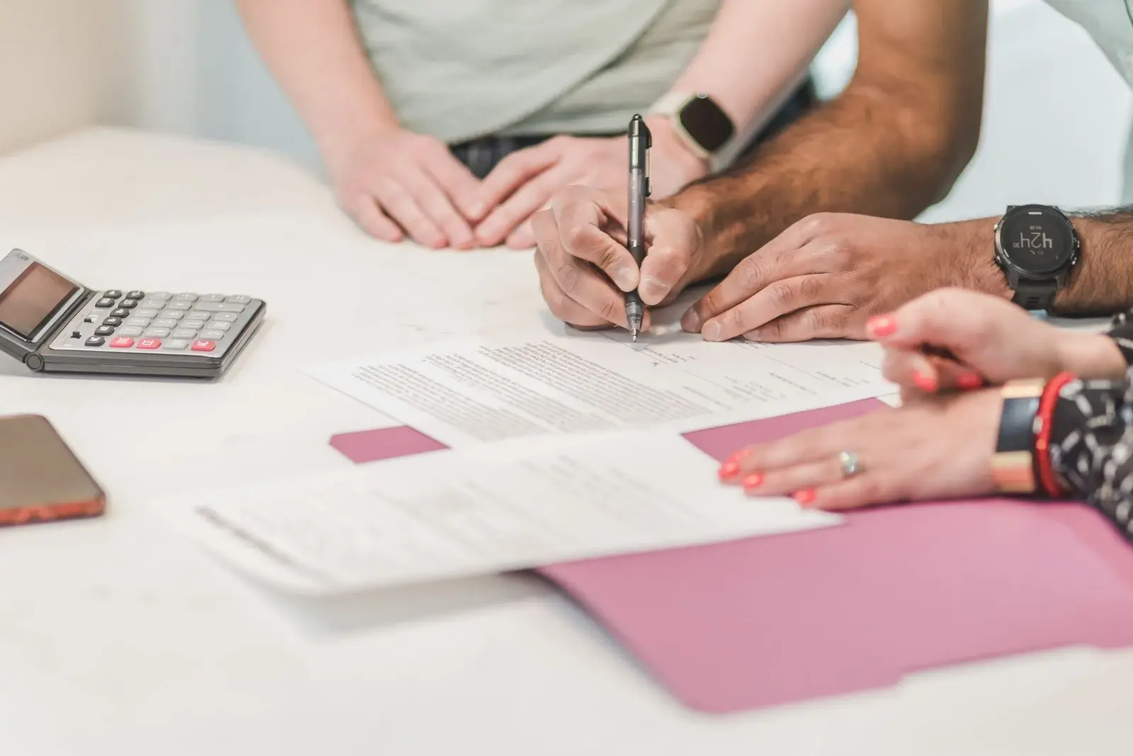 People reviewing and signing documents together at a table
